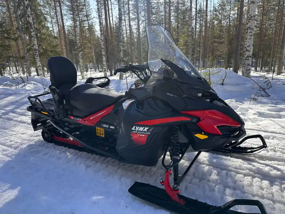 Black and red snowmobile in forest clearing
