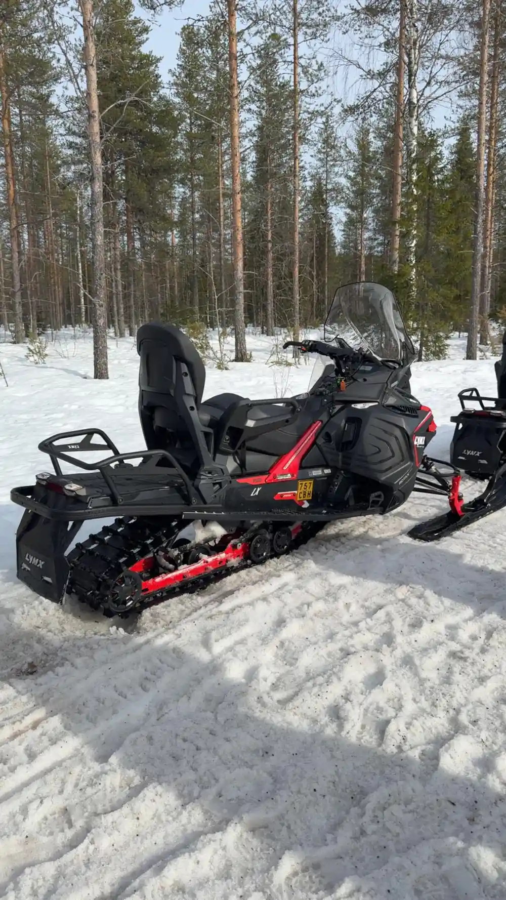 Close-up of red and black snowmobile parked in snow