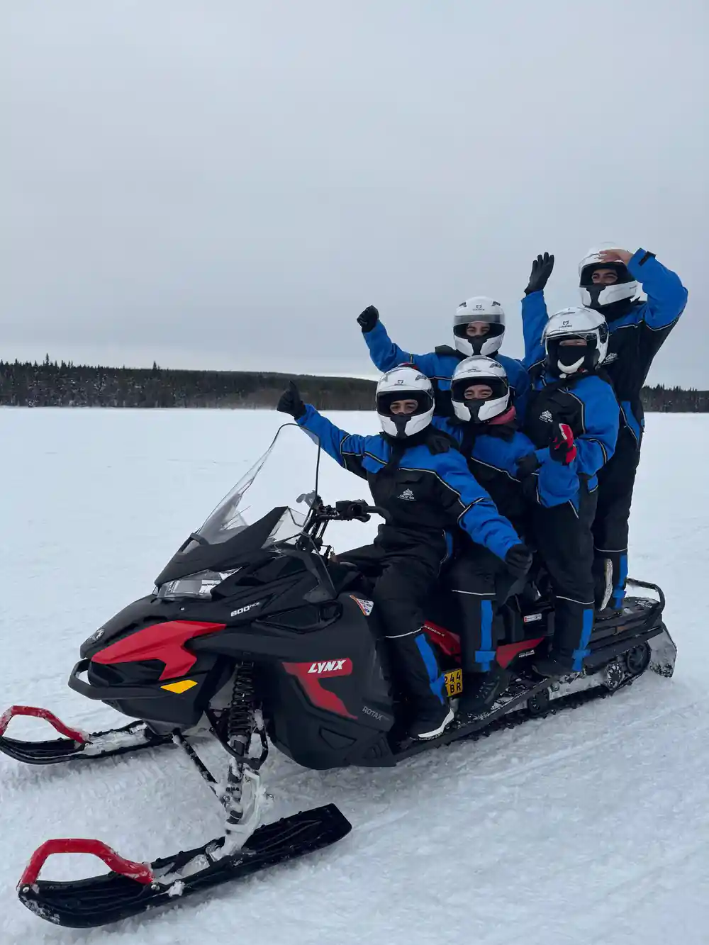 Group of people celebrating on snowmobile with raised arms