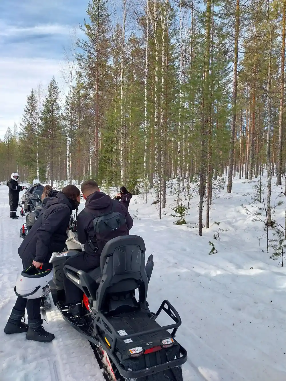 Group of people with snowmobiles in snowy forest