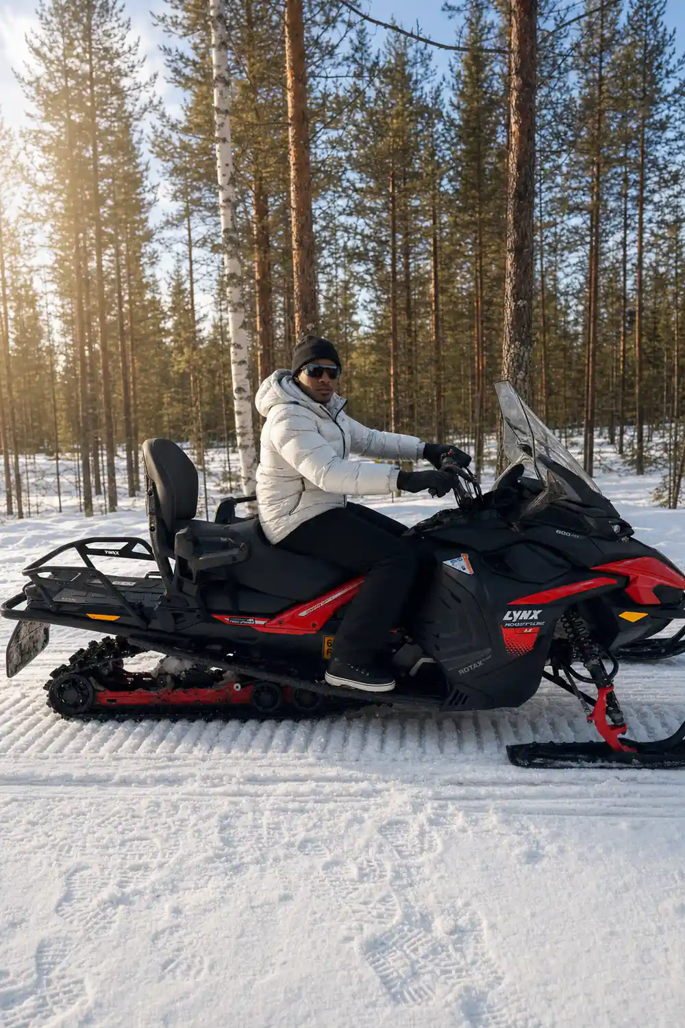 Person seated on red and black snowmobile in winter