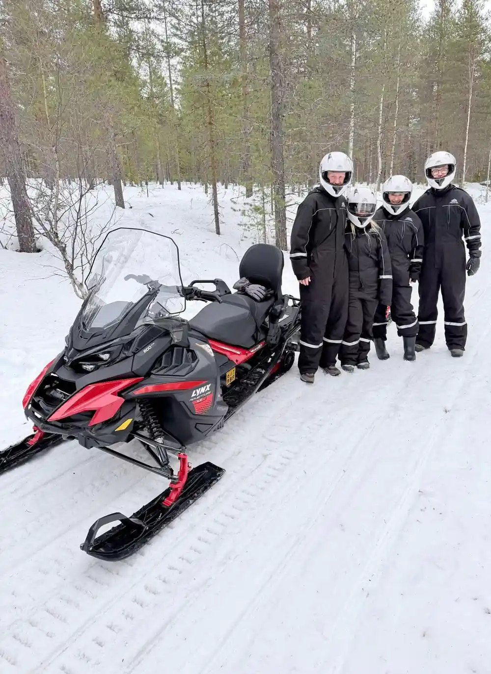 Red and black snowmobile with three people in winter gear