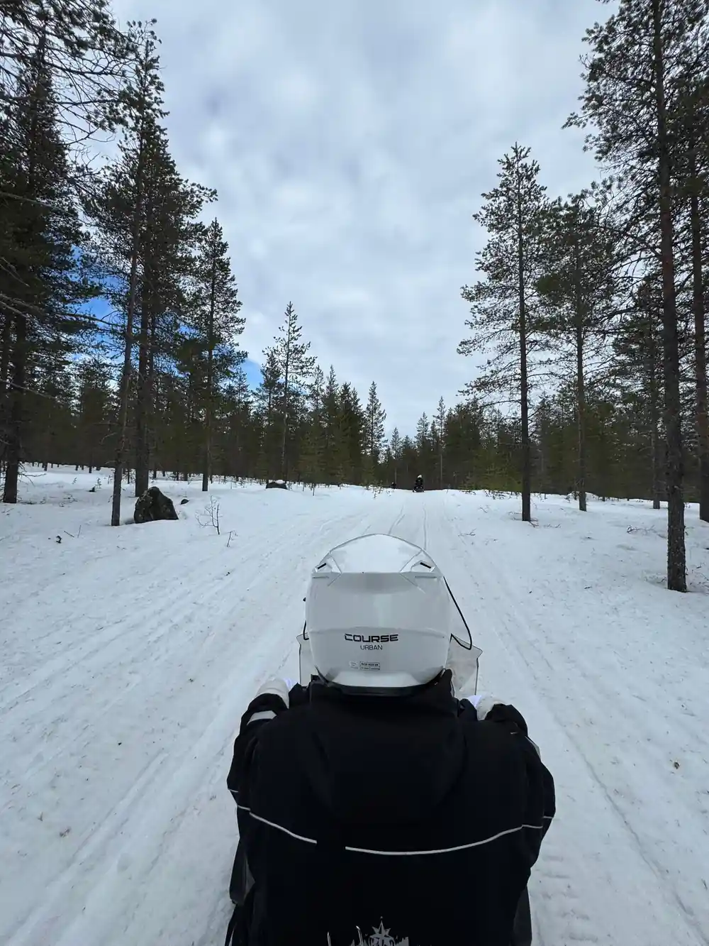 Three people standing near red and black snowmobile
