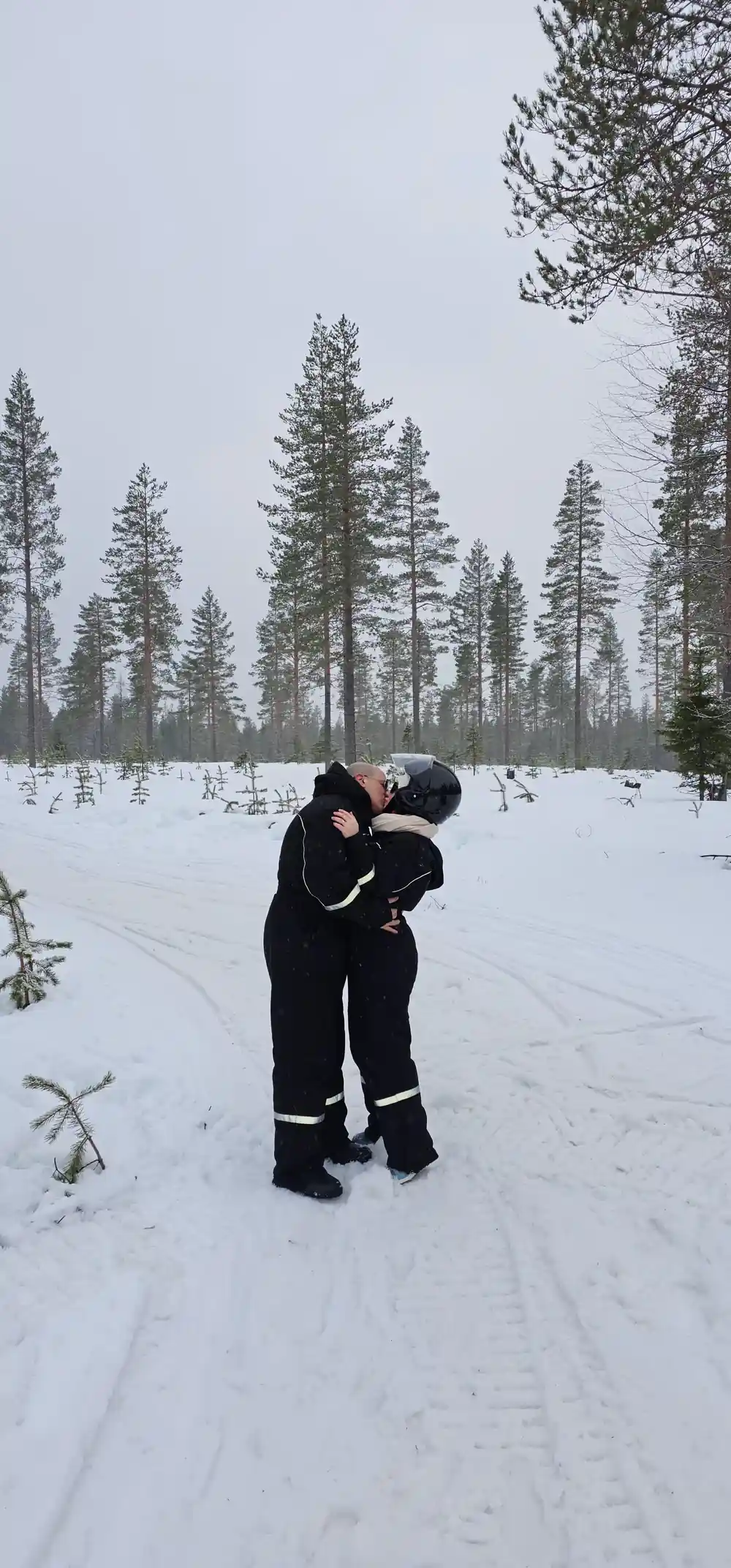Two people kissing in snowy forest landscape